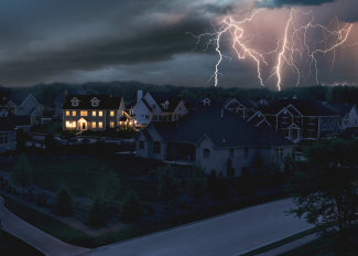 A single home with electric power supplied by a home generator during an outage. Lightning in the background