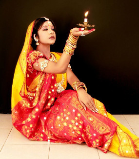 Image of Shipra Parish sitting on the floor holding a candle in the palm of her hand.